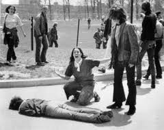 One of the four slain student demonstrators at Kent State lies on the ground as students look on in shock.
